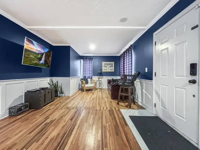 Interior space featuring light wood-type flooring, crown molding, and wainscoting