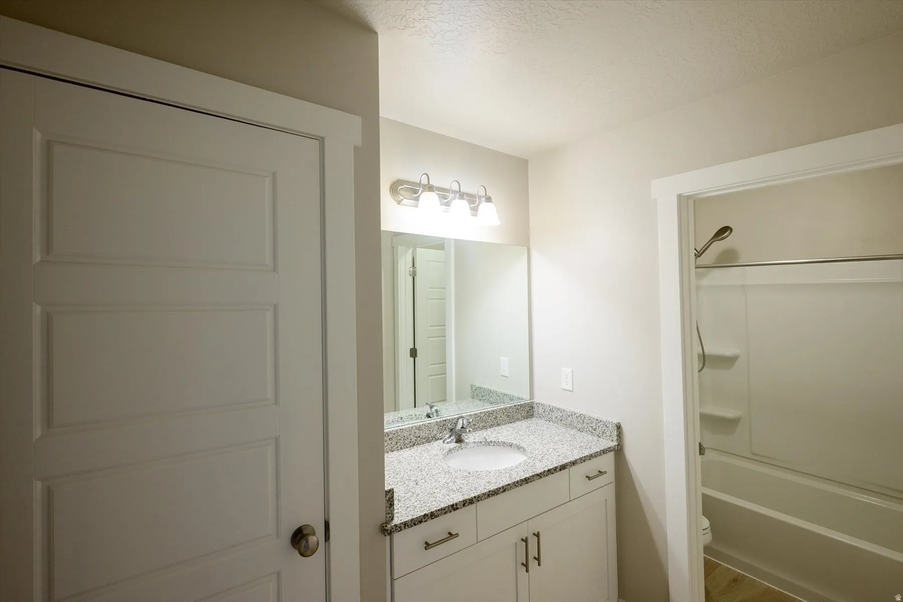 Full bath with vanity, bathtub / shower combination, and a textured ceiling