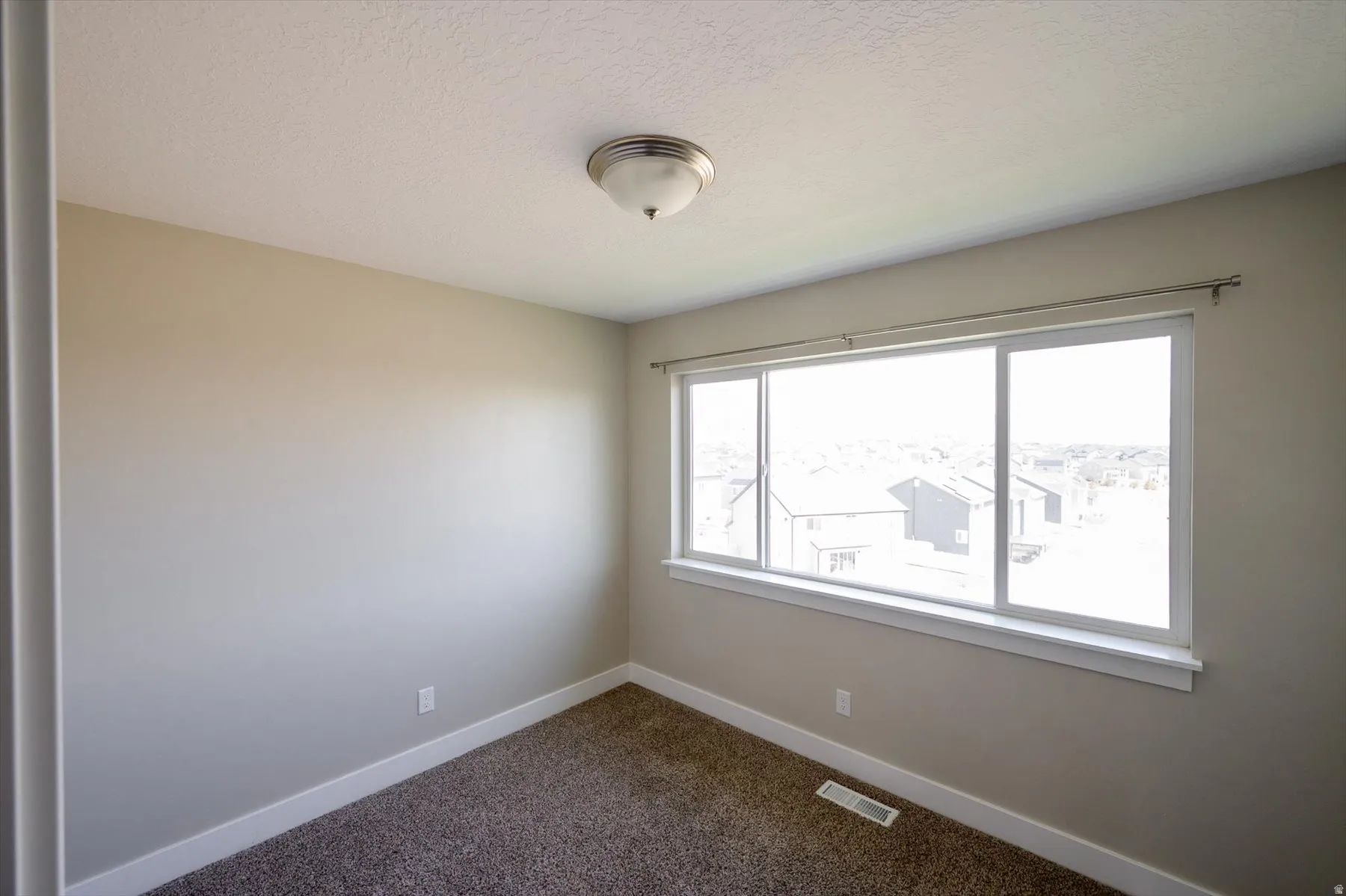 Empty room with dark colored carpet and a textured ceiling
