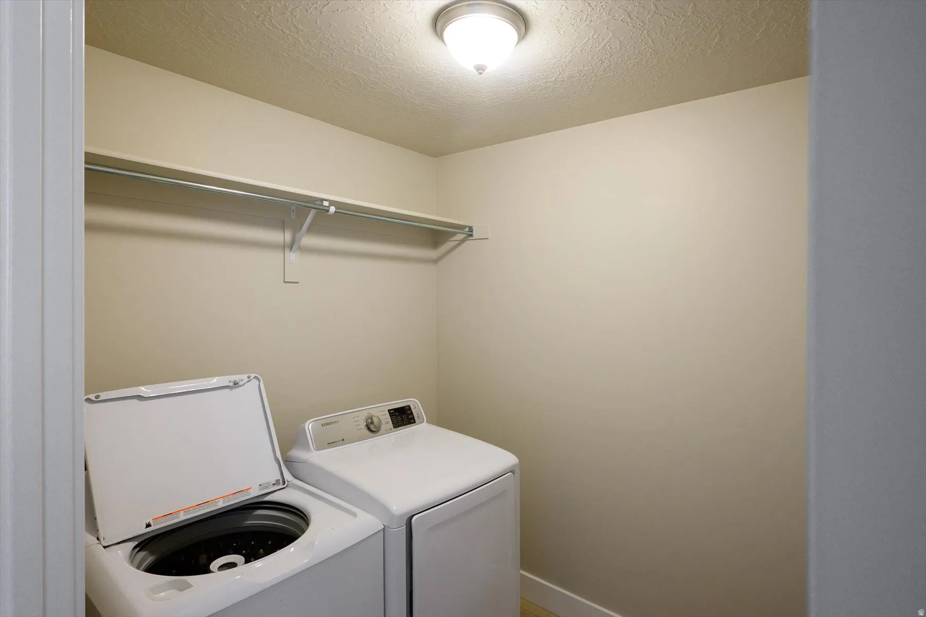 Laundry area featuring a textured ceiling and separate washer and dryer