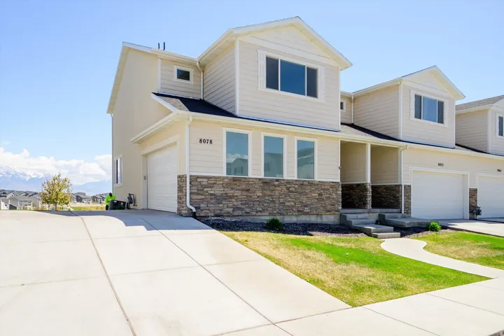 View of front of house with a garage, stone siding, a residential view, and driveway