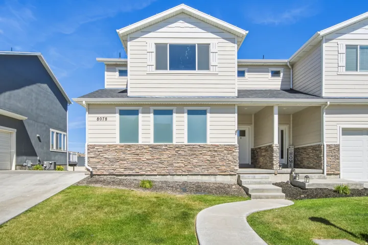 Two-story residence featuring light-colored siding and a stacked stone facade