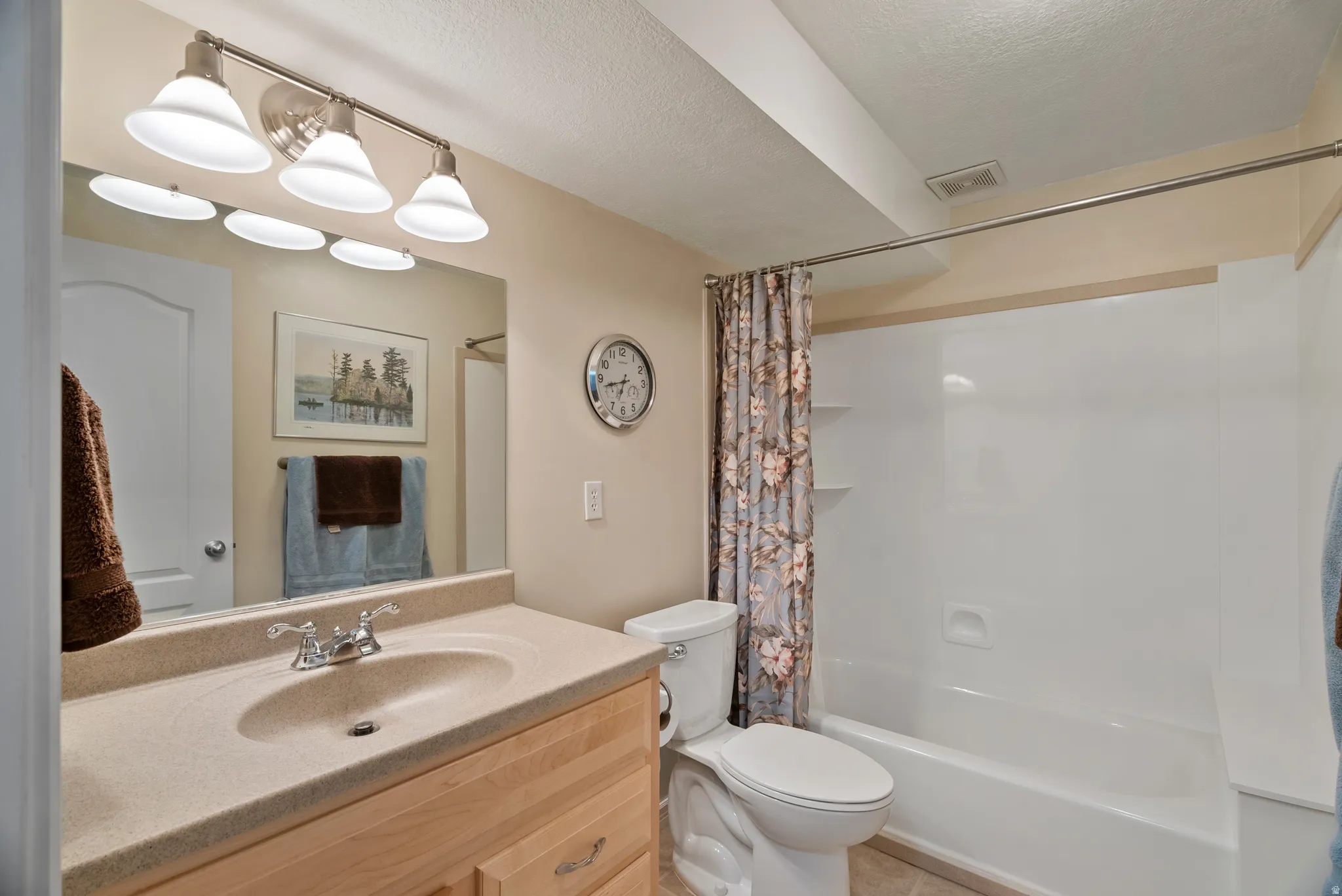 Bathroom featuring vanity, shower / bath combination with curtain, and a textured ceiling