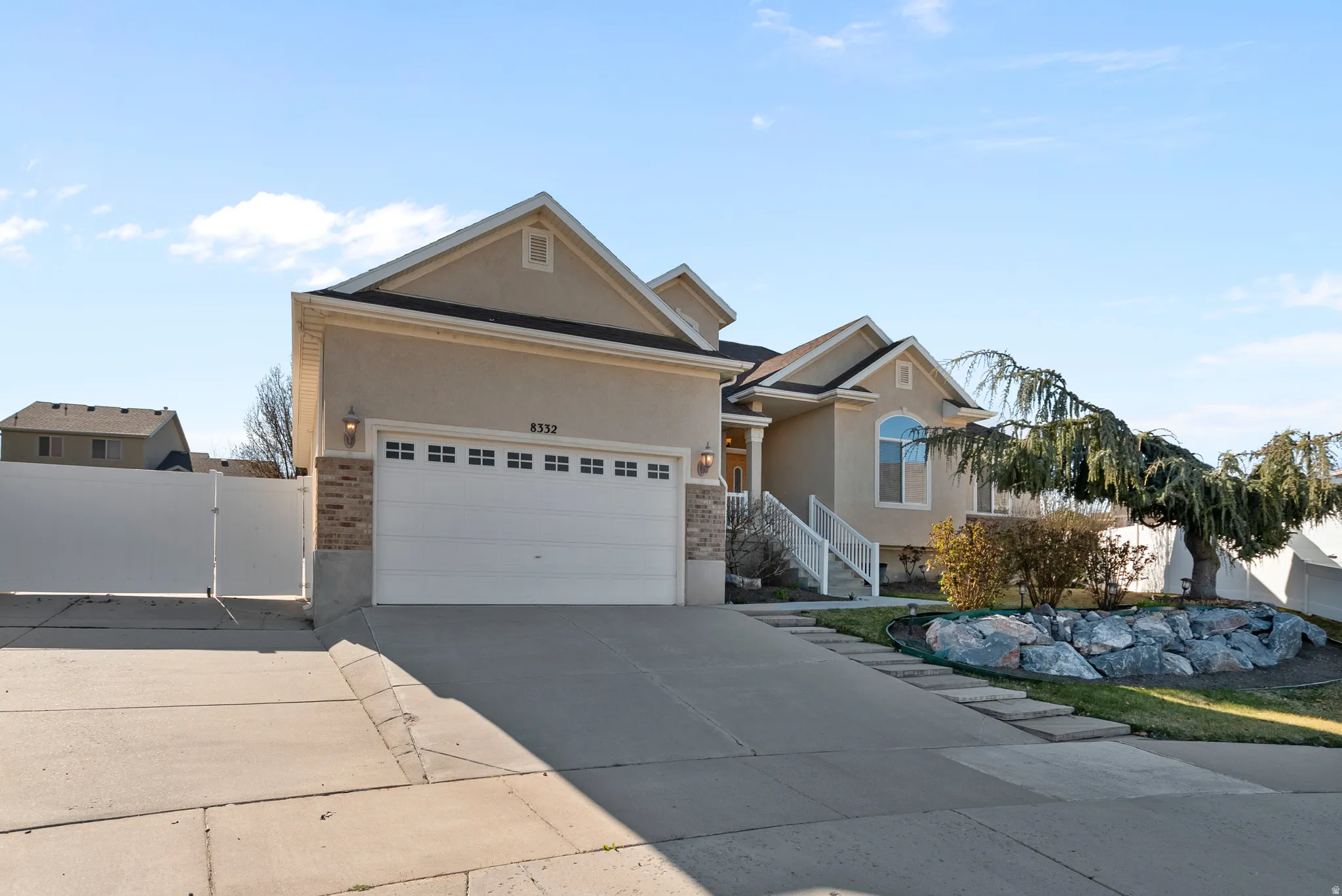 View of front facade with stucco siding, driveway, an attached garage, a gate, and brick siding