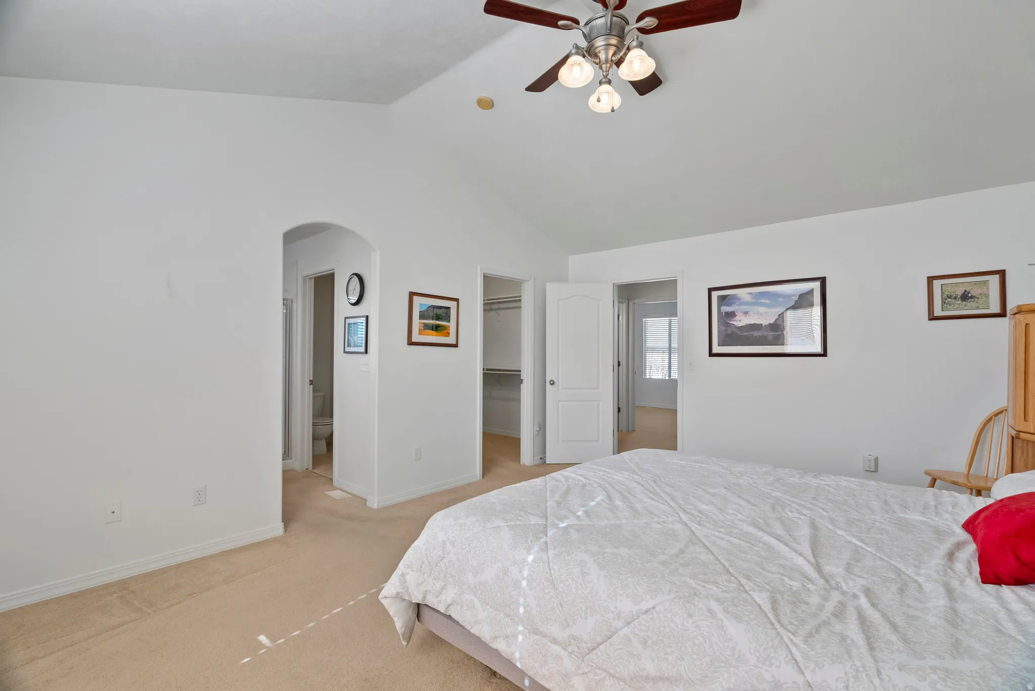 Bedroom with a spacious closet, arched walkways, ceiling fan, light carpet, and a high ceiling