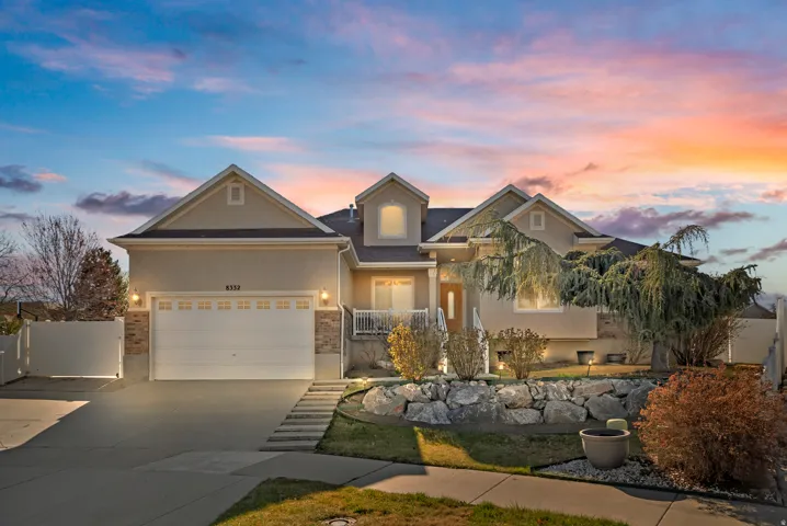View of front of house with concrete driveway, an attached garage, brick siding, stucco siding, and a gate