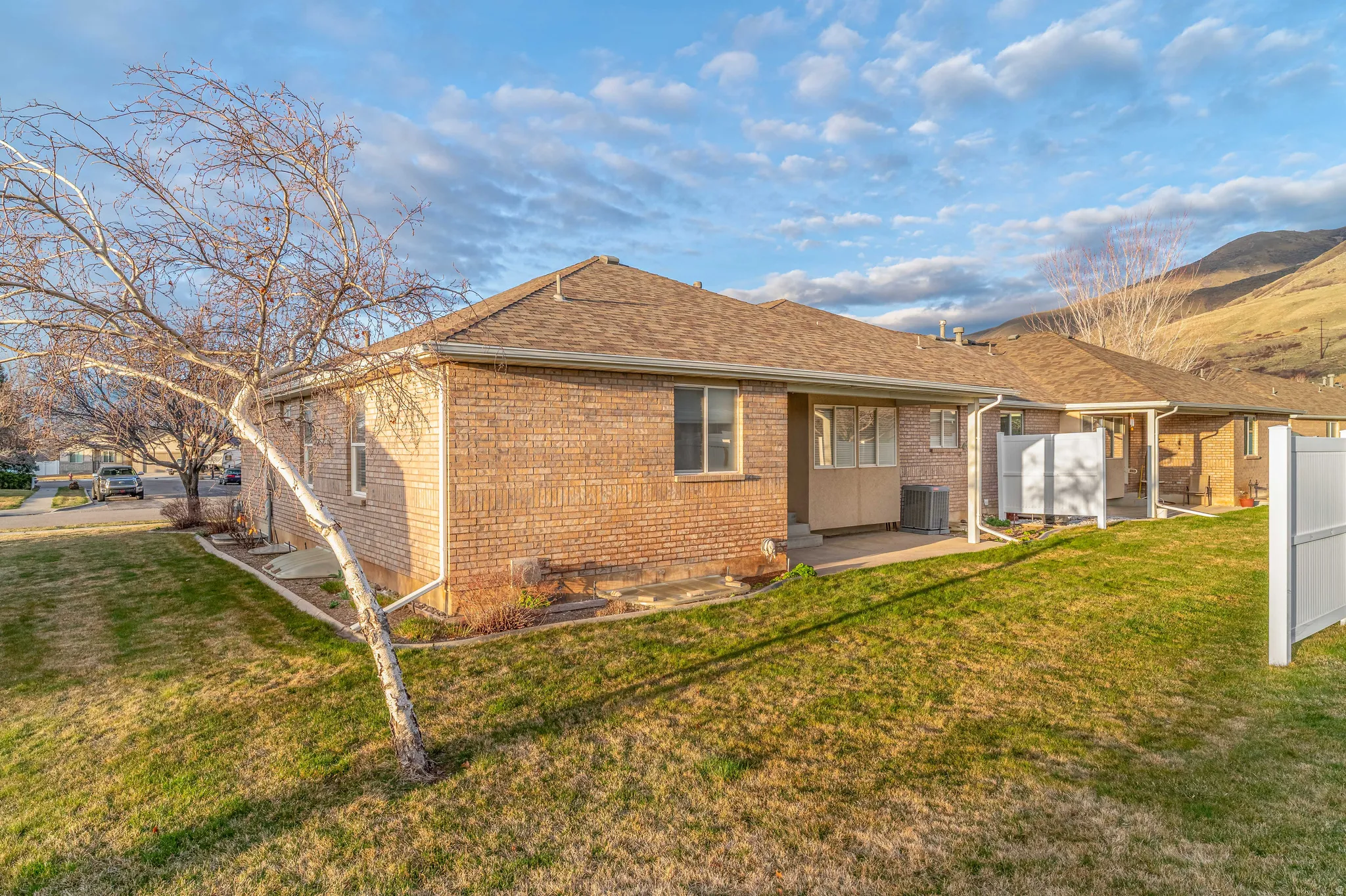 Rear view of house with a yard, a patio area, a shingled roof, and brick siding
