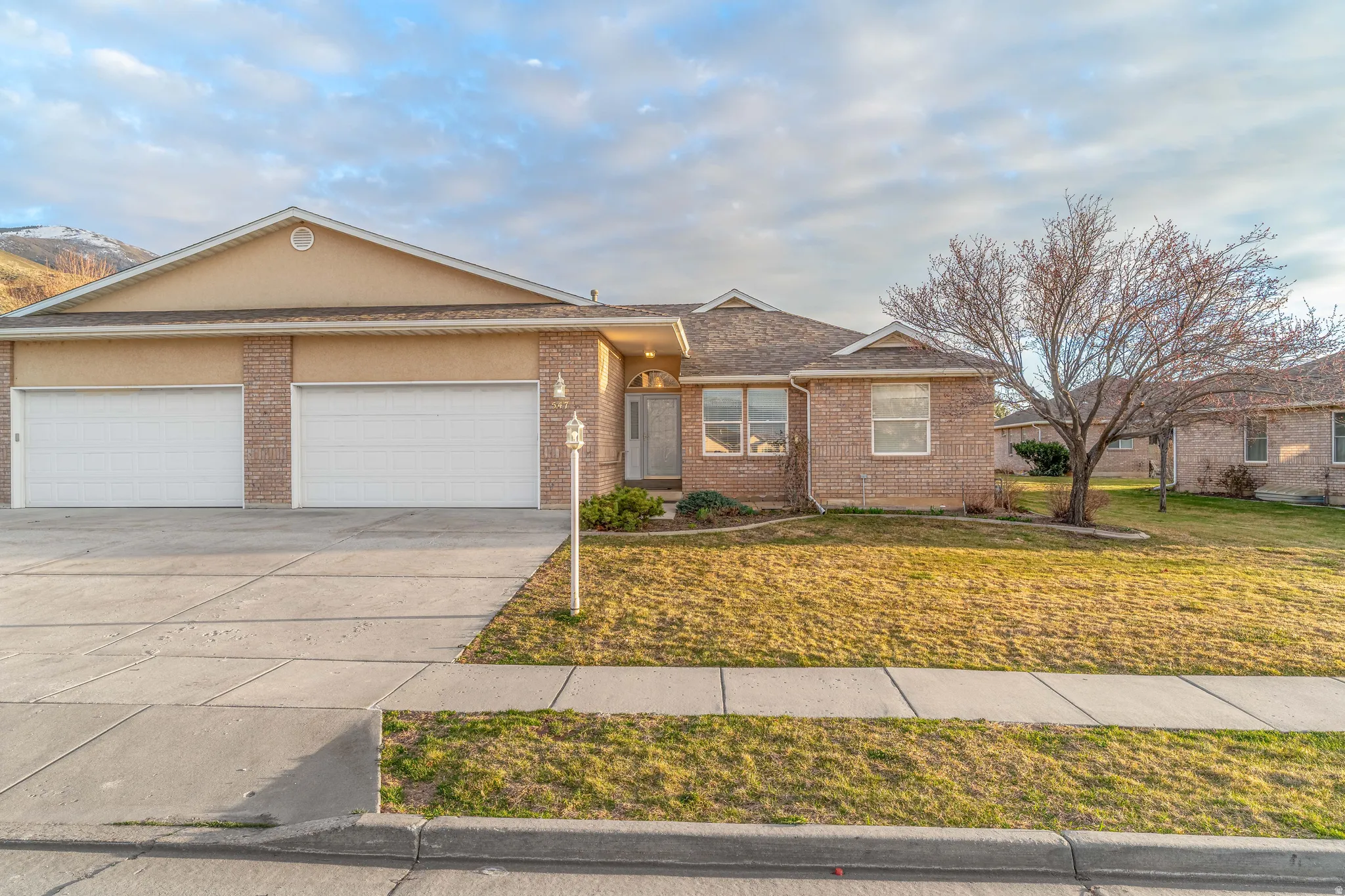 Single story home with a garage, concrete driveway, a front yard, and brick siding