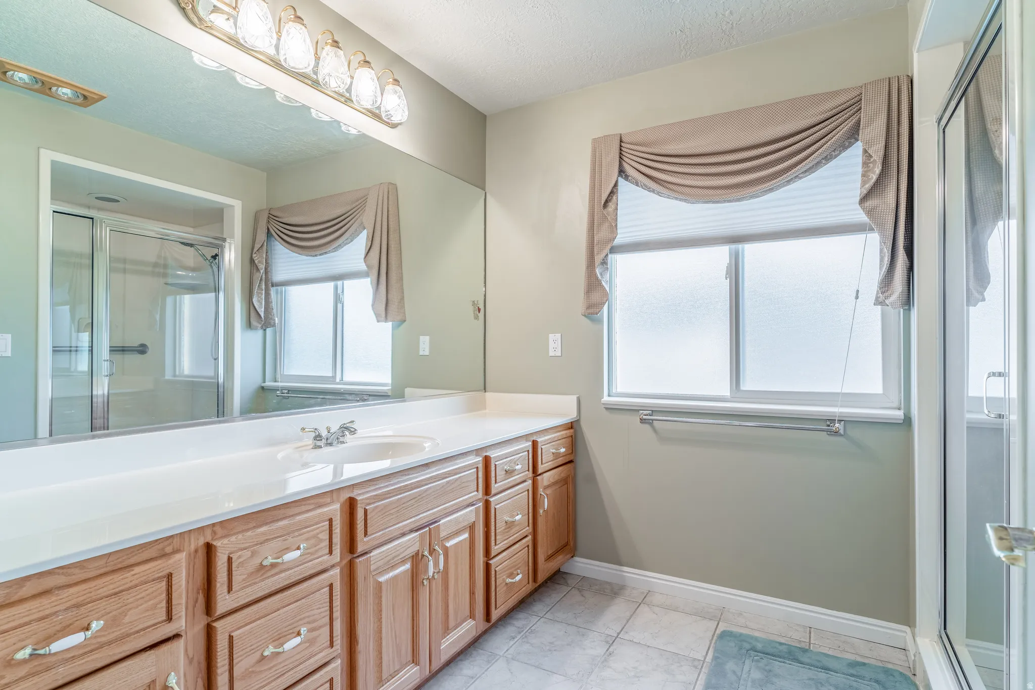 Bathroom with a shower stall, vanity, and light tile patterned flooring