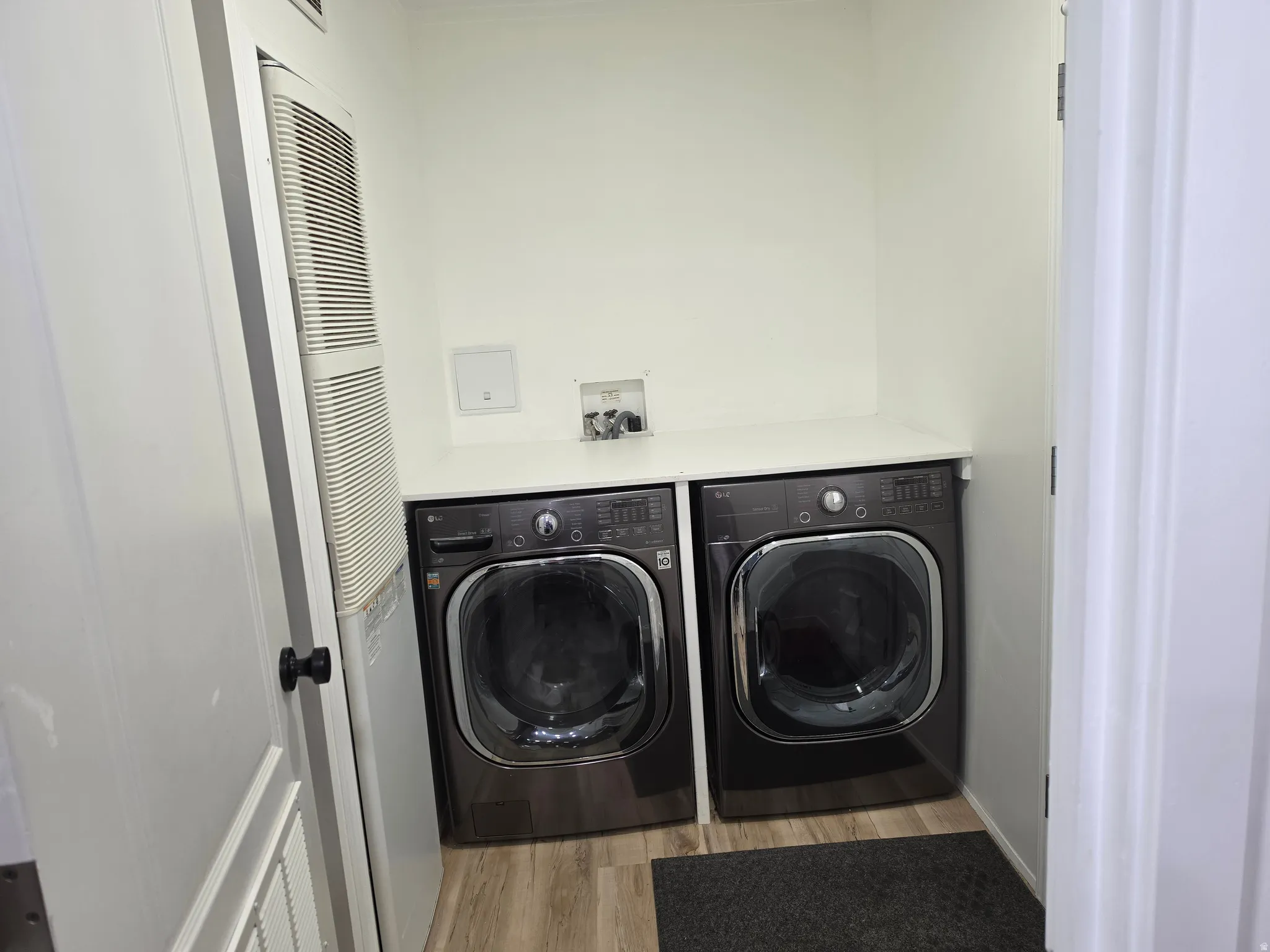 Laundry area featuring a heating unit, light wood-type flooring, and separate washer and dryer