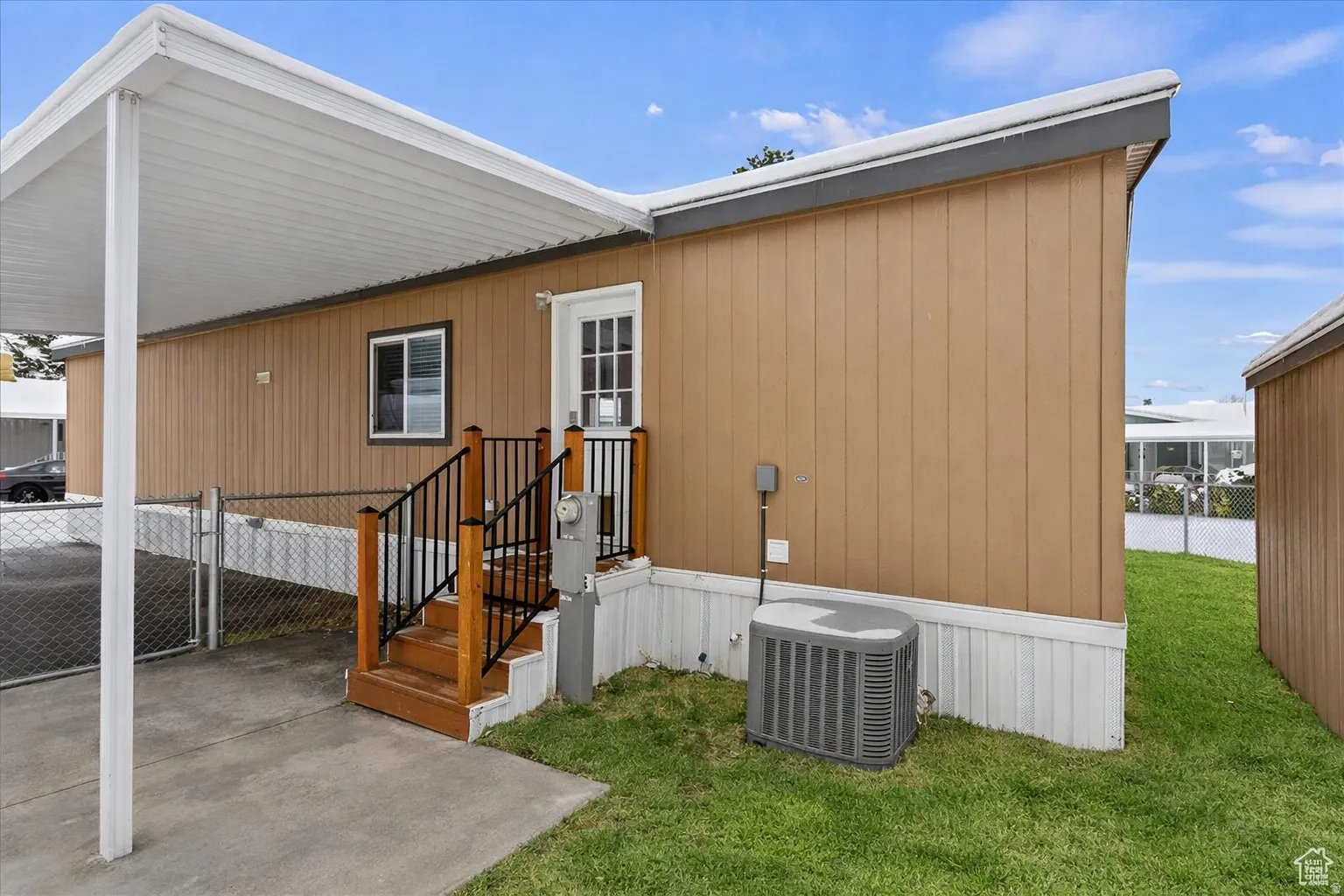View of side of home featuring an attached carport and a gate