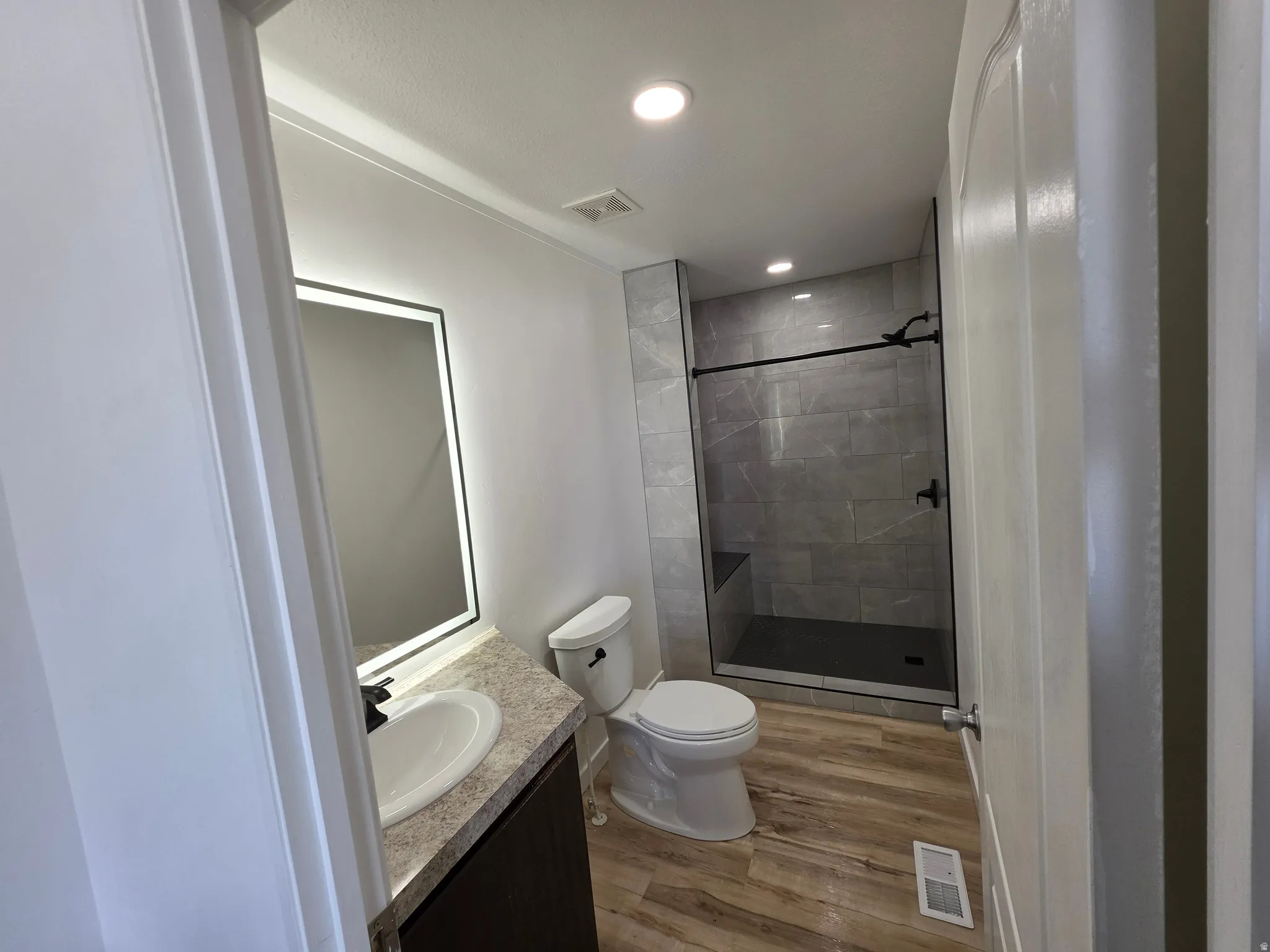 Full bath featuring a shower stall, vanity, wood finished floors, and recessed lighting