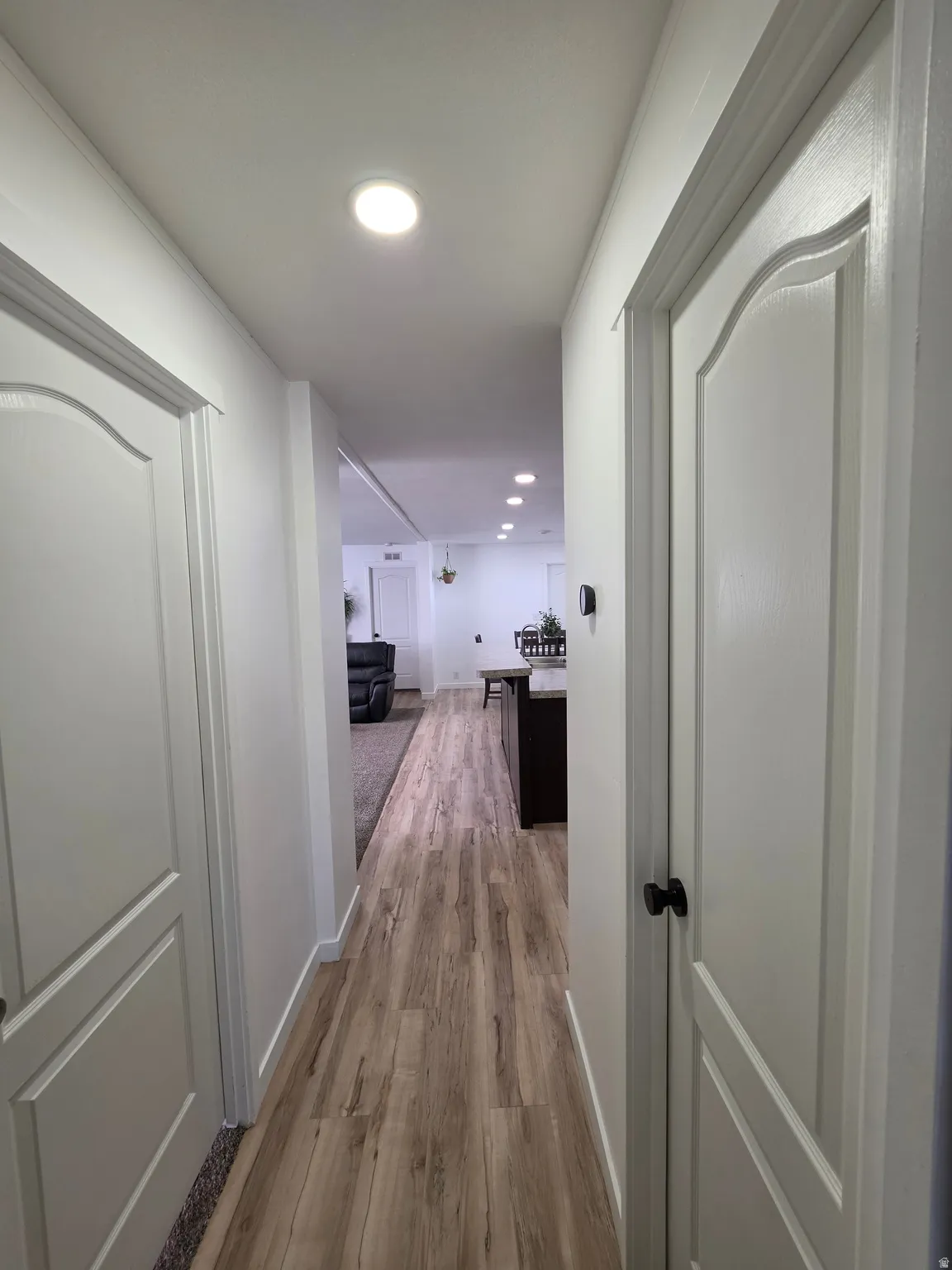 Hall with light wood-type flooring and recessed lighting