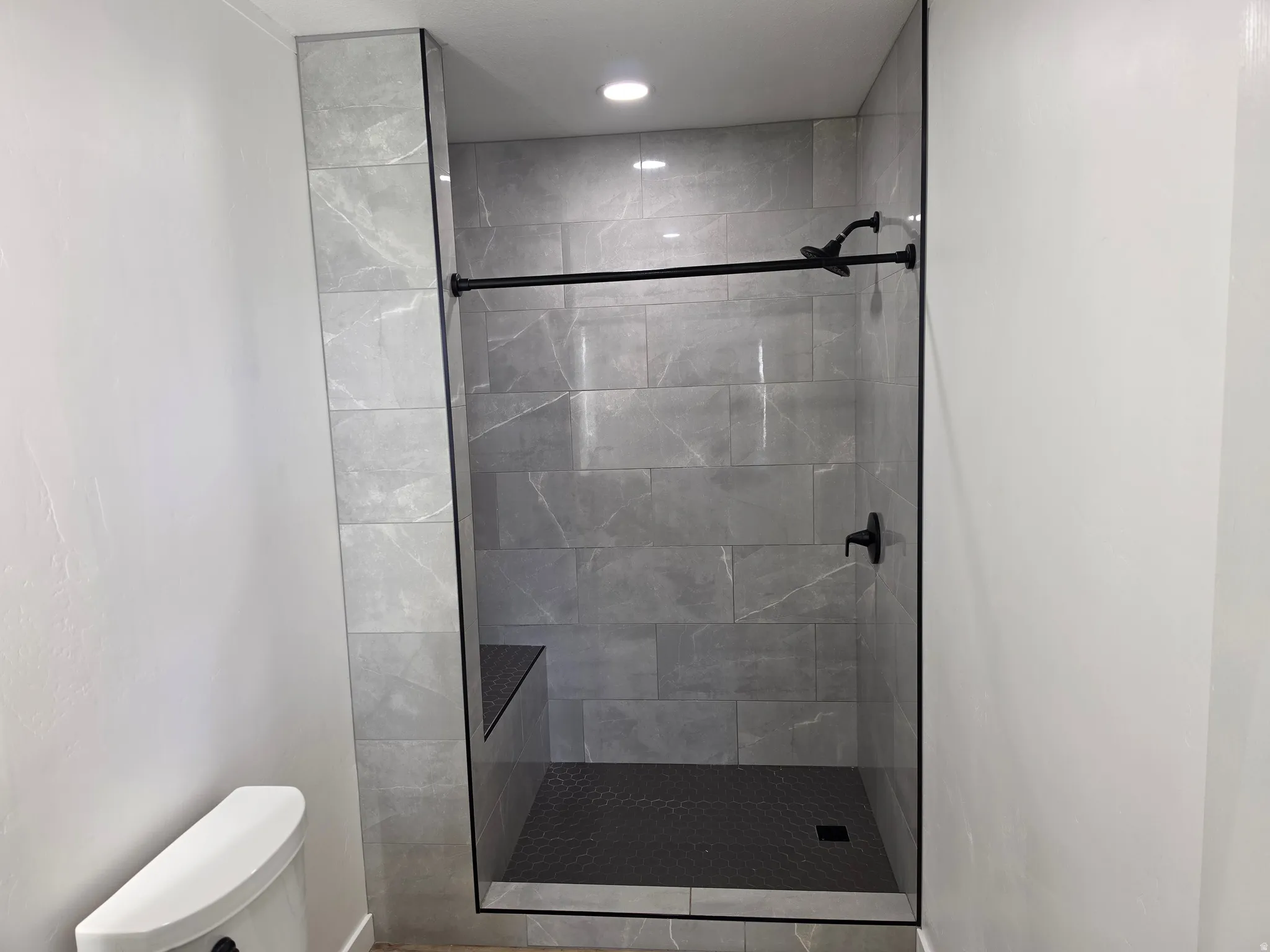 Bathroom featuring a tile shower and toilet