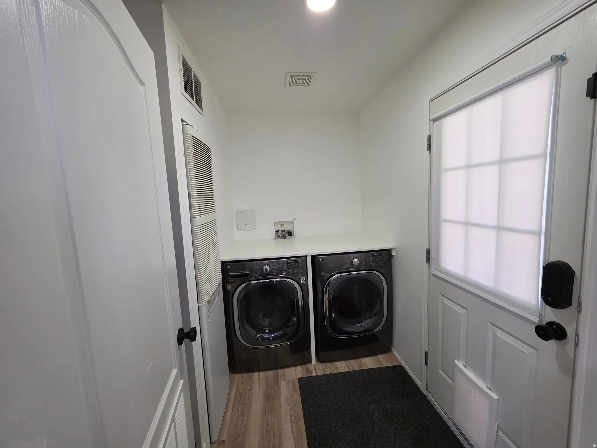 Laundry area featuring light wood-style flooring, a heating unit, and washing machine and dryer
