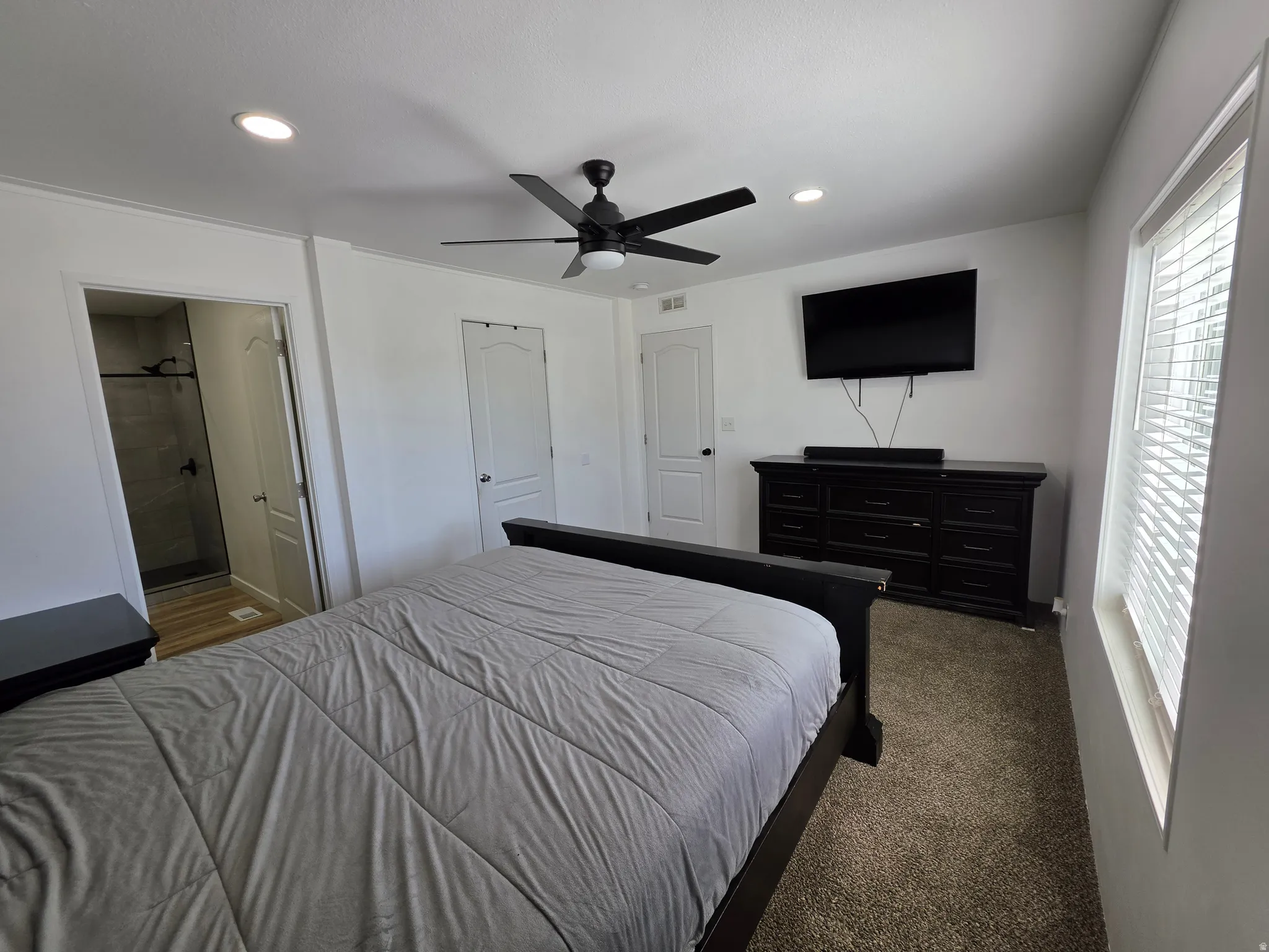 Bedroom with dark carpet, a ceiling fan, recessed lighting, and ensuite bath