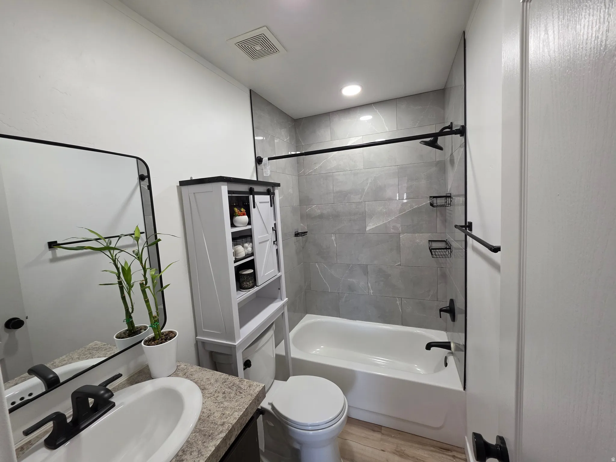 Bathroom with vanity, tub / shower combination, light wood-type flooring, and recessed lighting
