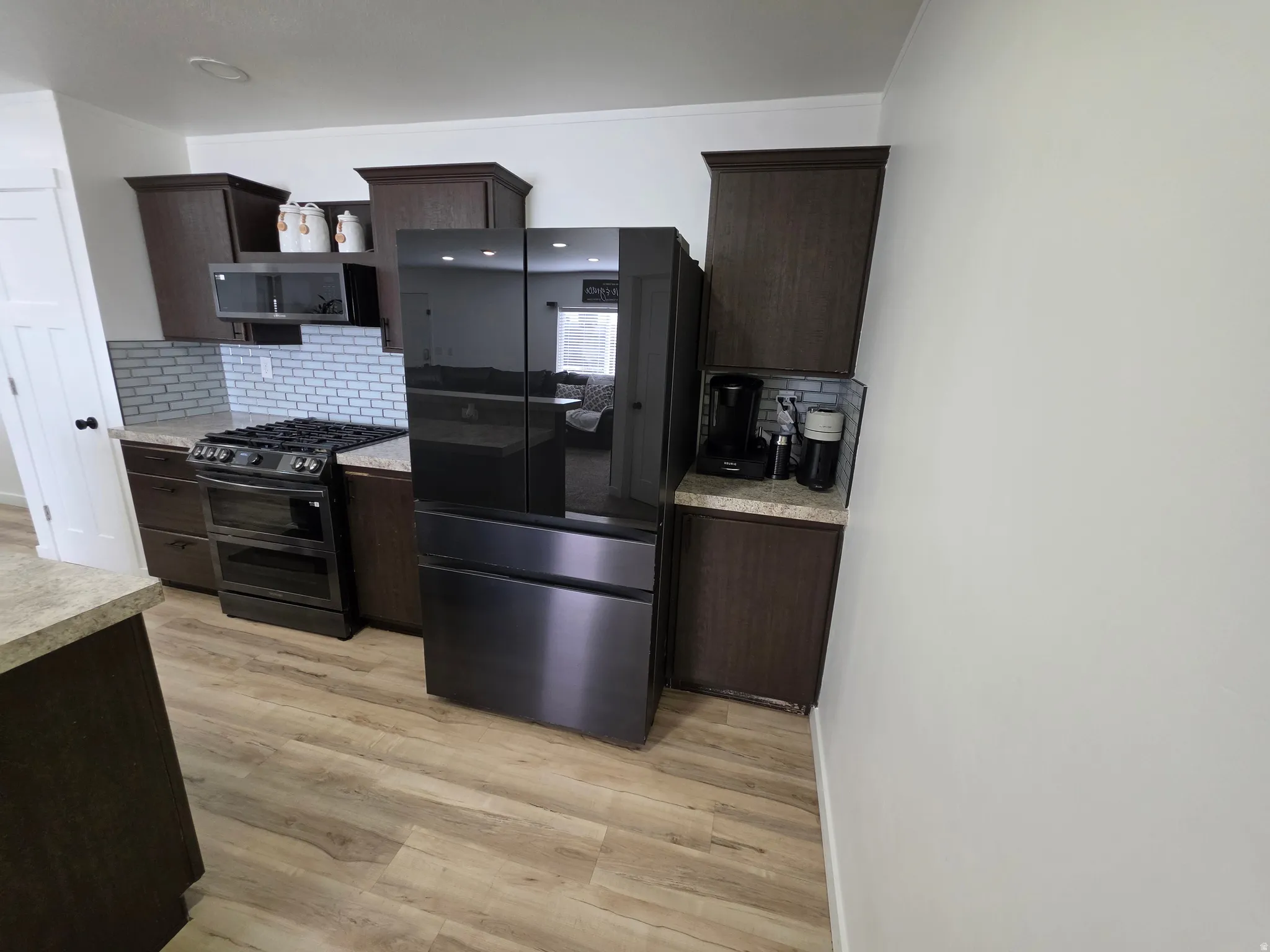 Kitchen featuring dark wood finish cabinetry, range with two ovens, light countertops, and light wood finished floors