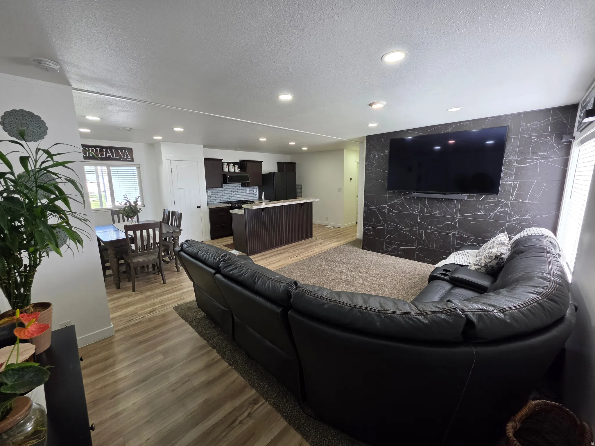 Living room featuring dark wood-style flooring, recessed lighting, an accent wall, and a textured ceiling