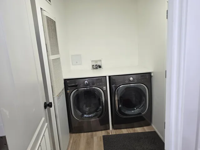 Laundry area featuring a heating unit, light wood-type flooring, and separate washer and dryer