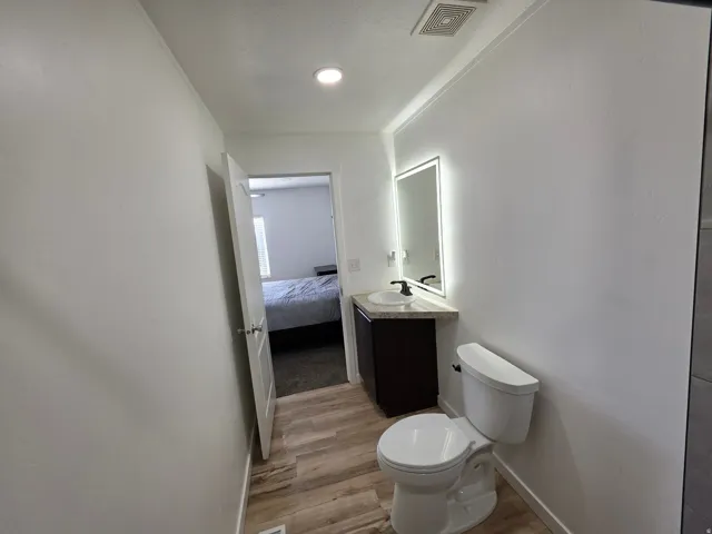 Ensuite bathroom featuring vanity and light wood-style floors