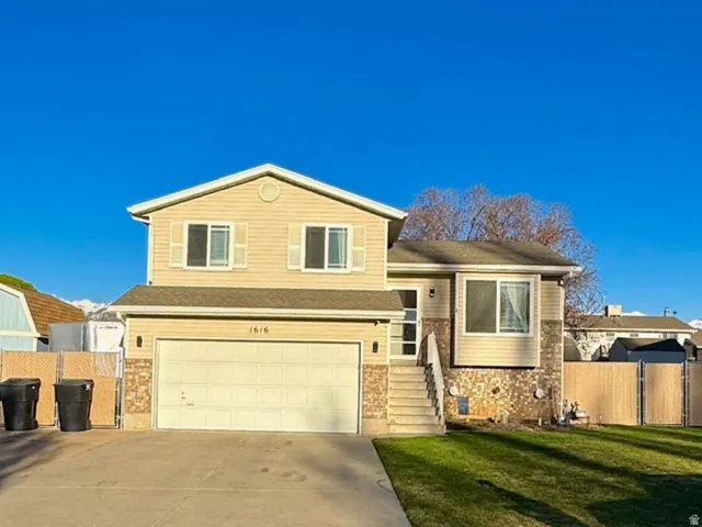 View of front of property with driveway, an attached garage, and brick siding and fenced RV Pad