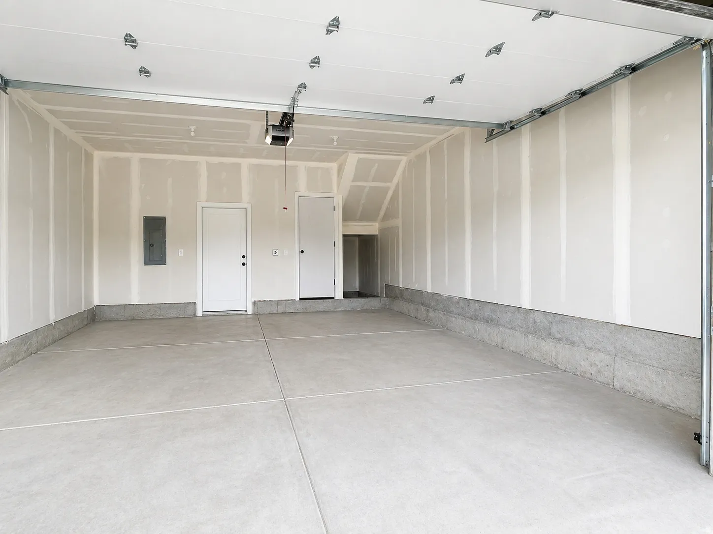 Spacious garage featuring concrete flooring and two entry doors