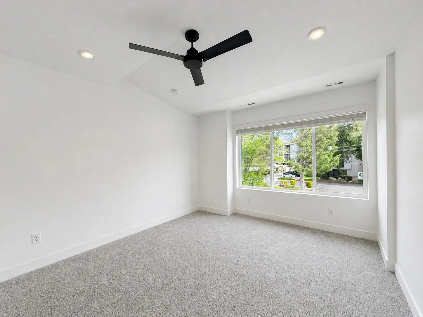 Carpeted room featuring a large window, recessed lighting, and a black ceiling fan