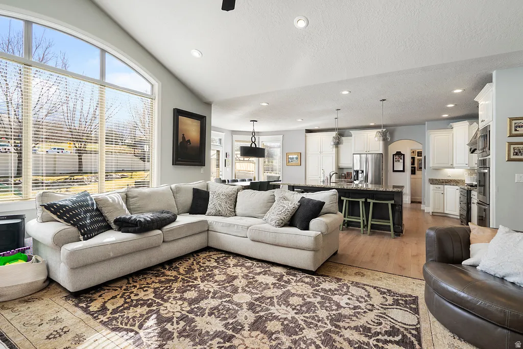 Living room featuring arched walkways, light wood-style floors, and recessed lighting