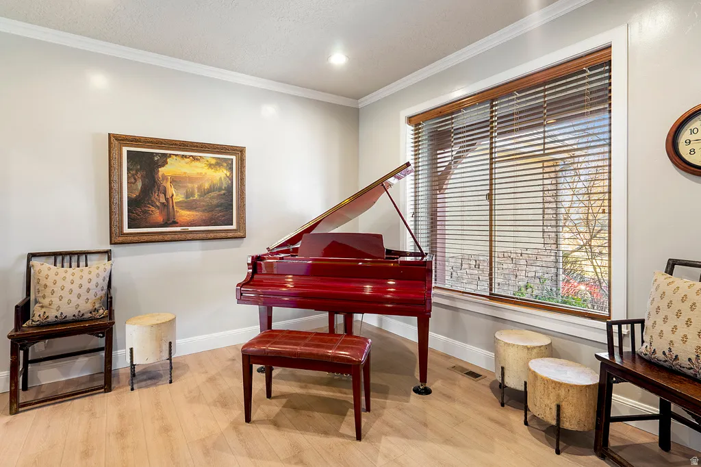 Sitting room with ornamental molding and light wood-style floors