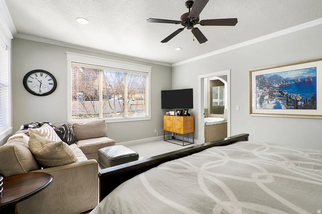 Carpeted bedroom with ornamental molding, a ceiling fan, connected bathroom, a textured ceiling, and recessed lighting