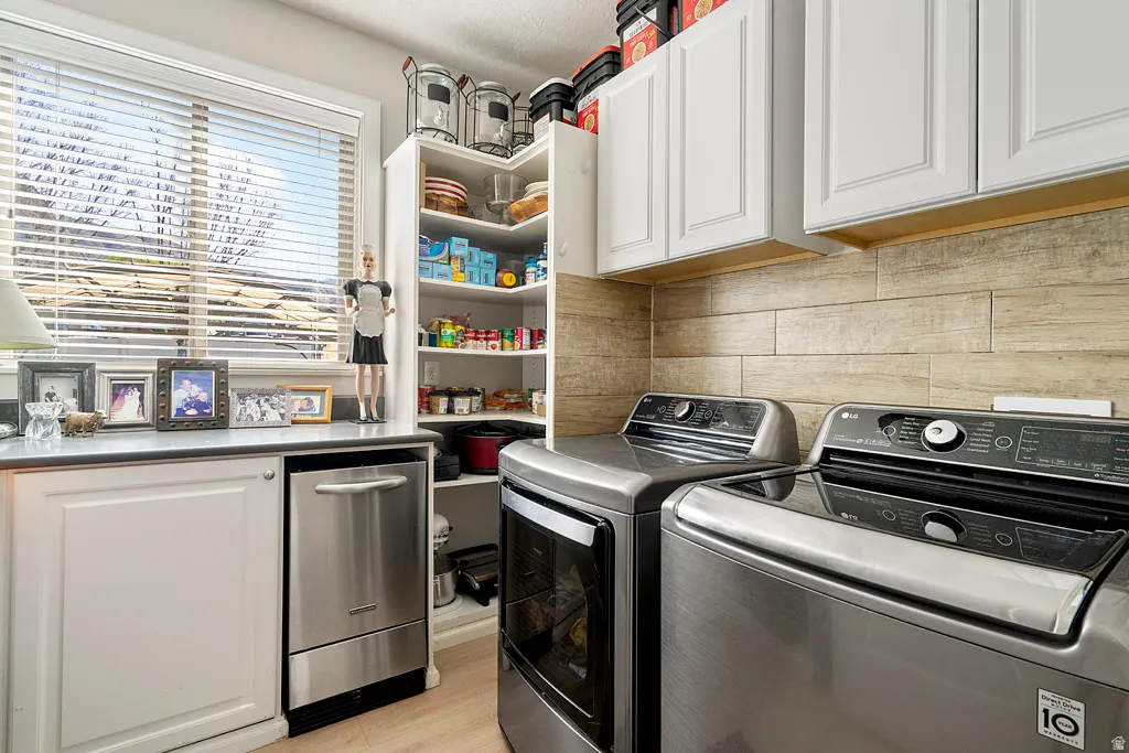 Laundry room featuring cabinet space, separate washer and dryer, and light wood-type flooring