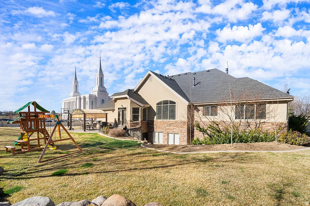 Rear view of property featuring roof with shingles, a yard, and a patio area