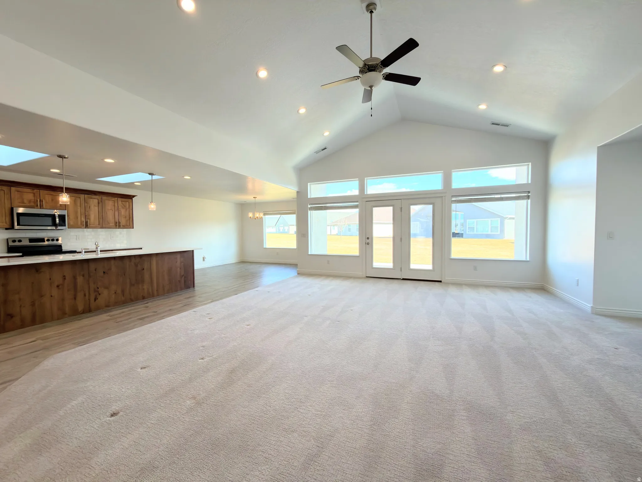 Unfurnished living room featuring recessed lighting, a ceiling fan, and a high ceiling