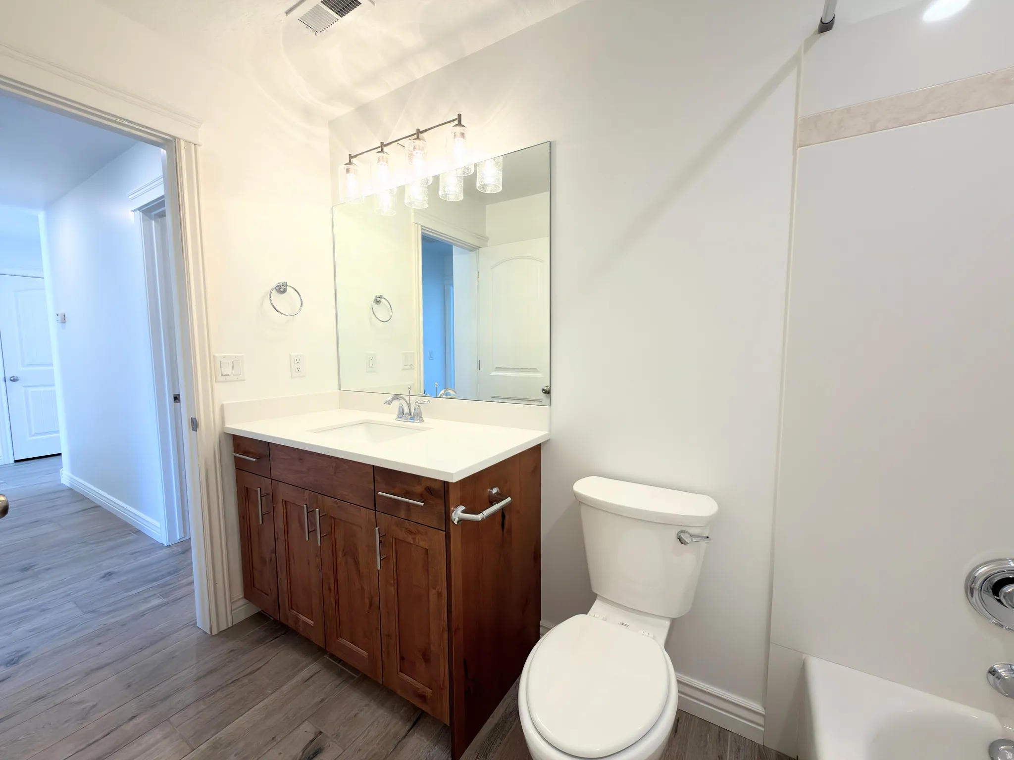 Bathroom featuring vanity, dark wood-style flooring, and shower / bathtub combination