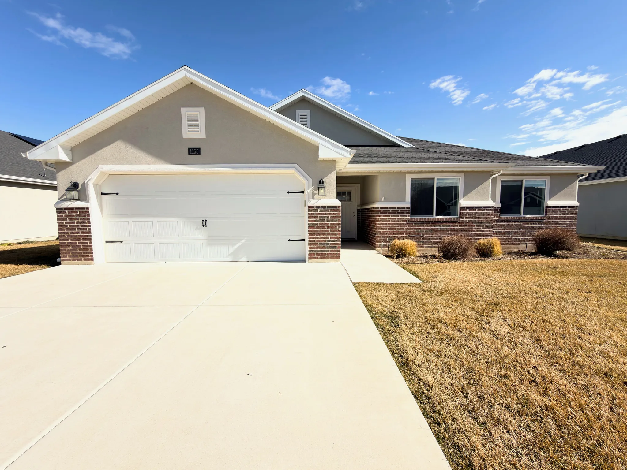 Single story home with brick siding, an attached garage, concrete driveway, and a front yard