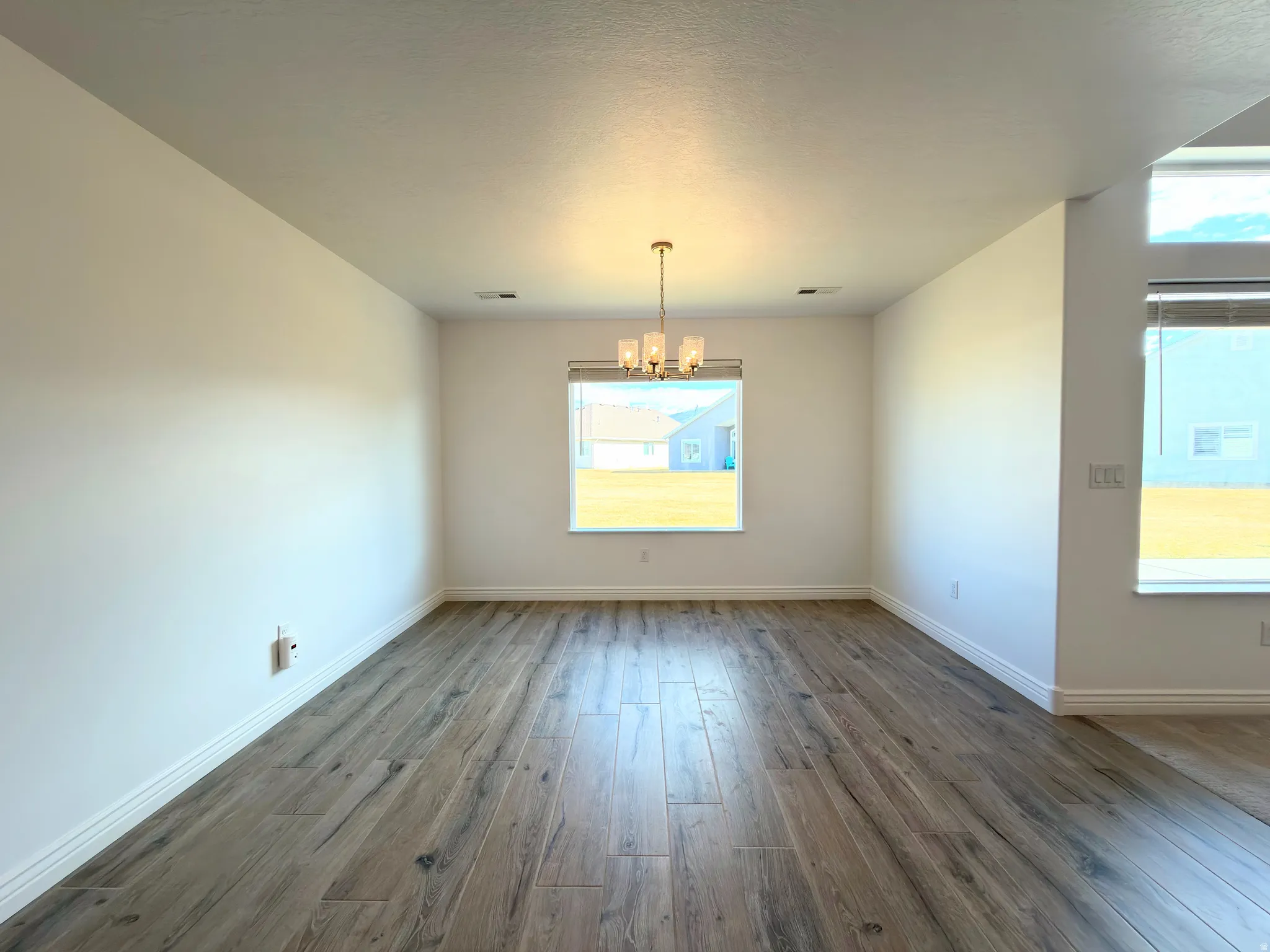 Unfurnished dining area featuring dark wood-type flooring and a chandelier