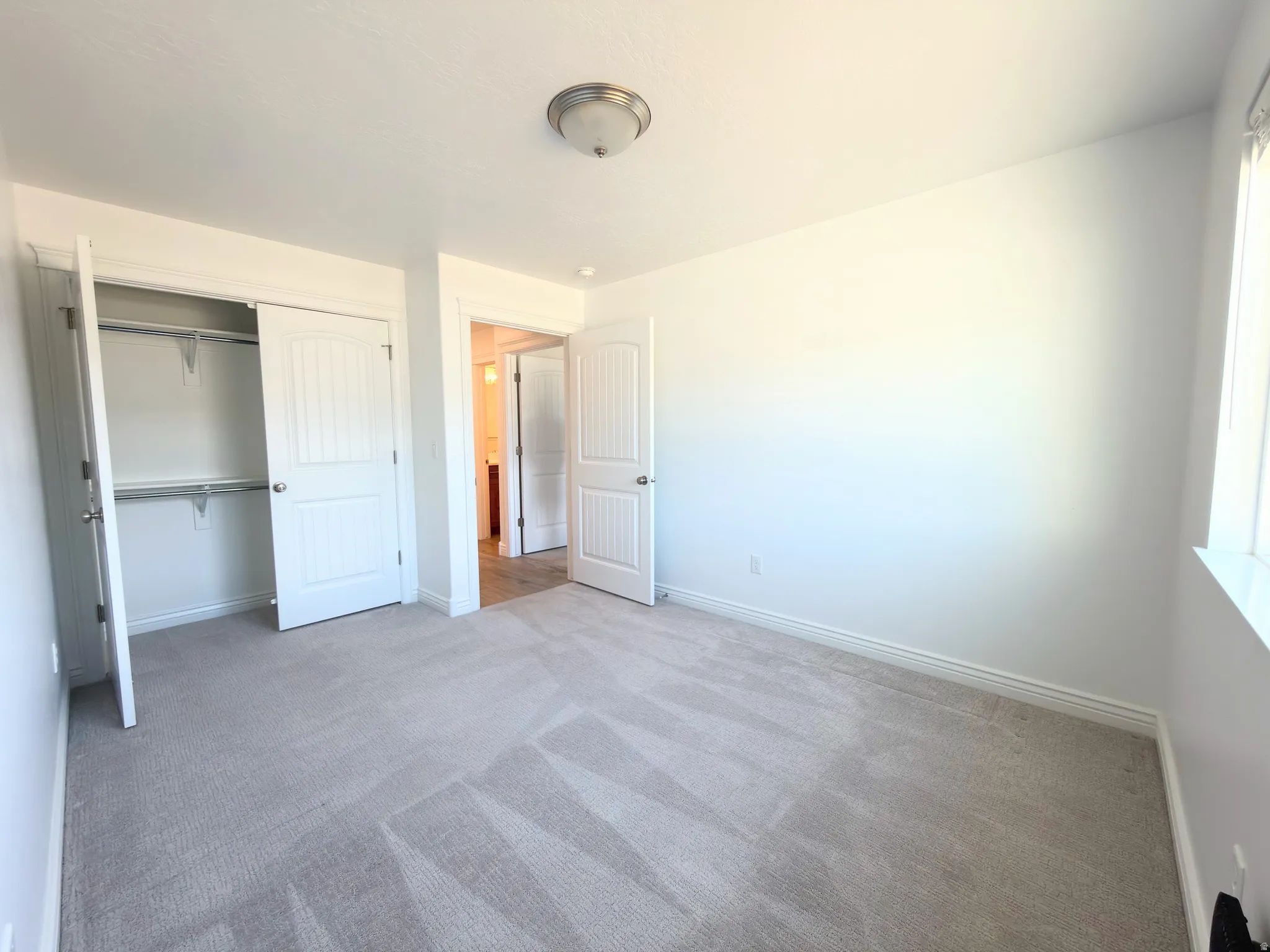 Unfurnished bedroom featuring light carpet and a closet