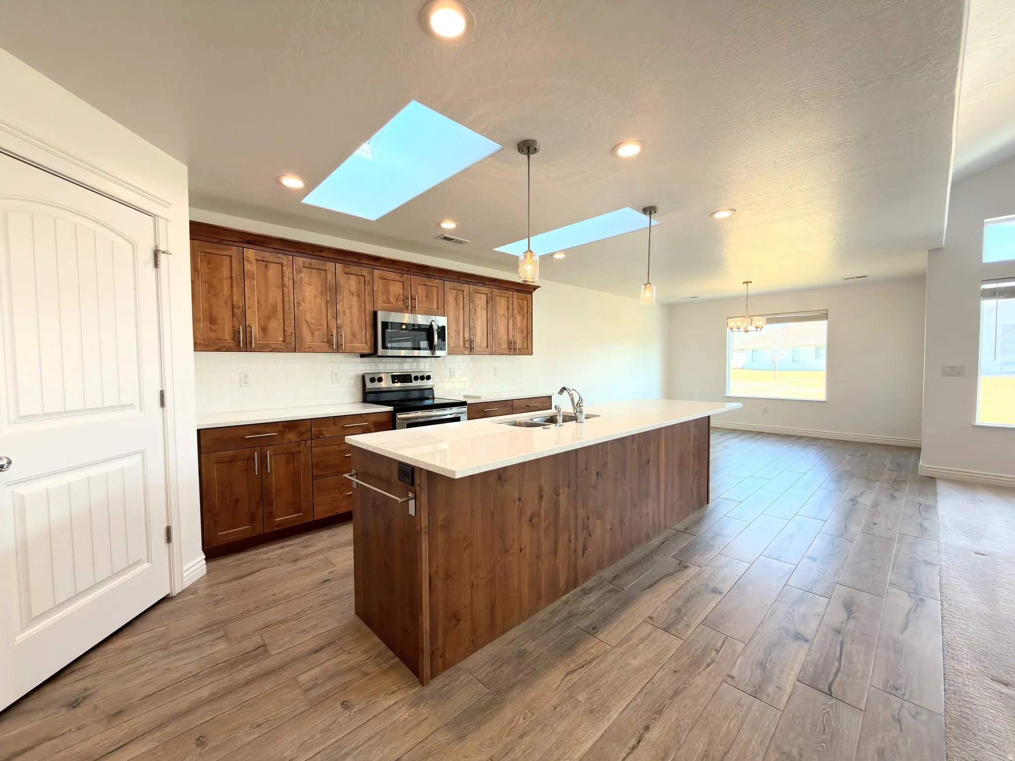 Kitchen featuring a skylight, light wood-style flooring, hanging light fixtures, and stainless steel appliances
