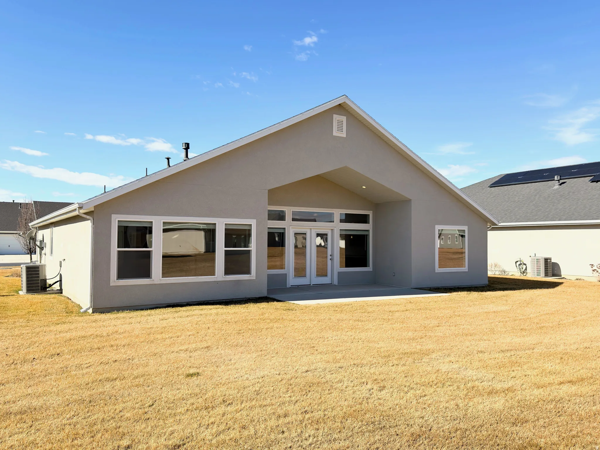 Back of property featuring stucco siding, a patio, french doors, and a lawn