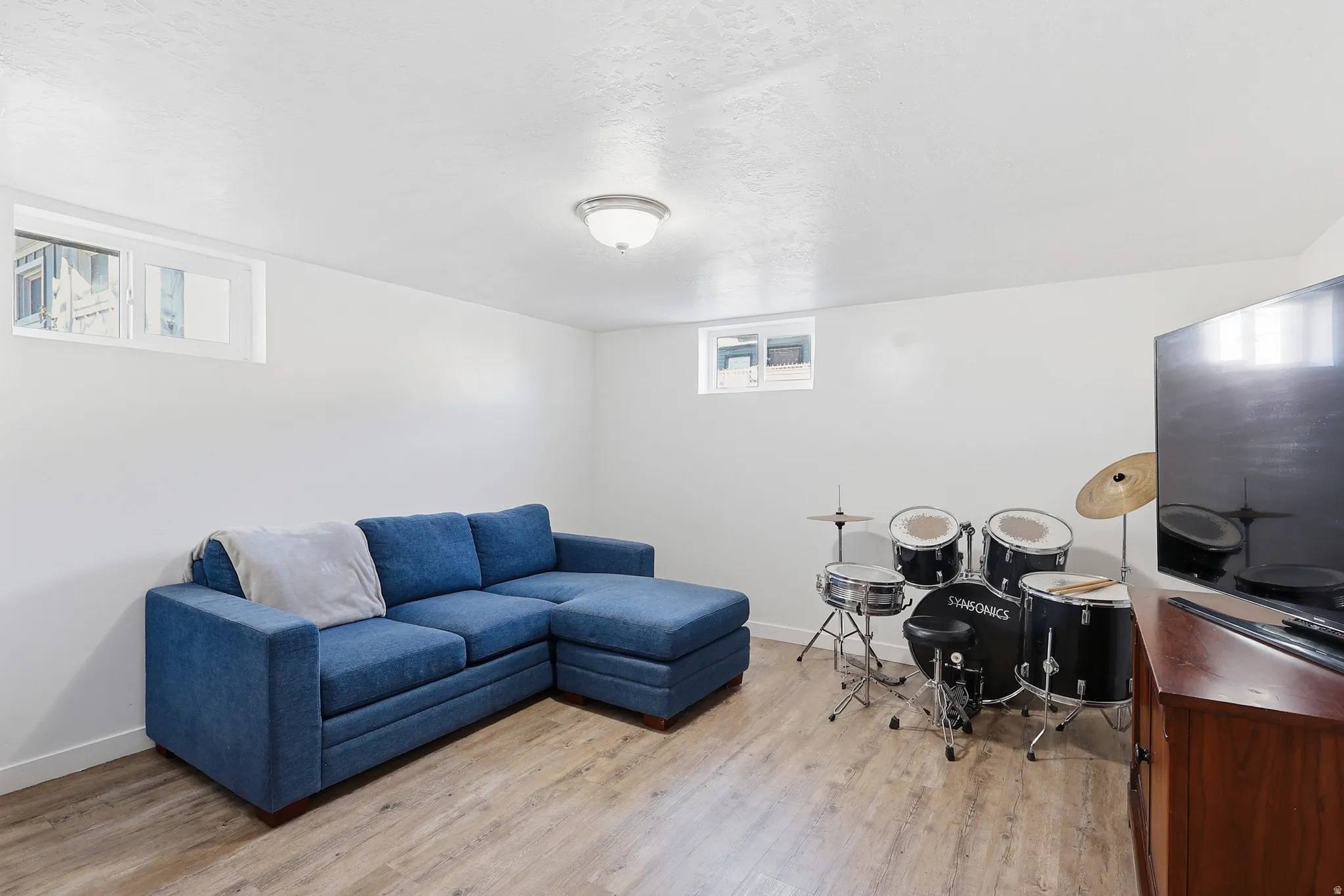 Home office with light wood-type flooring and a textured ceiling