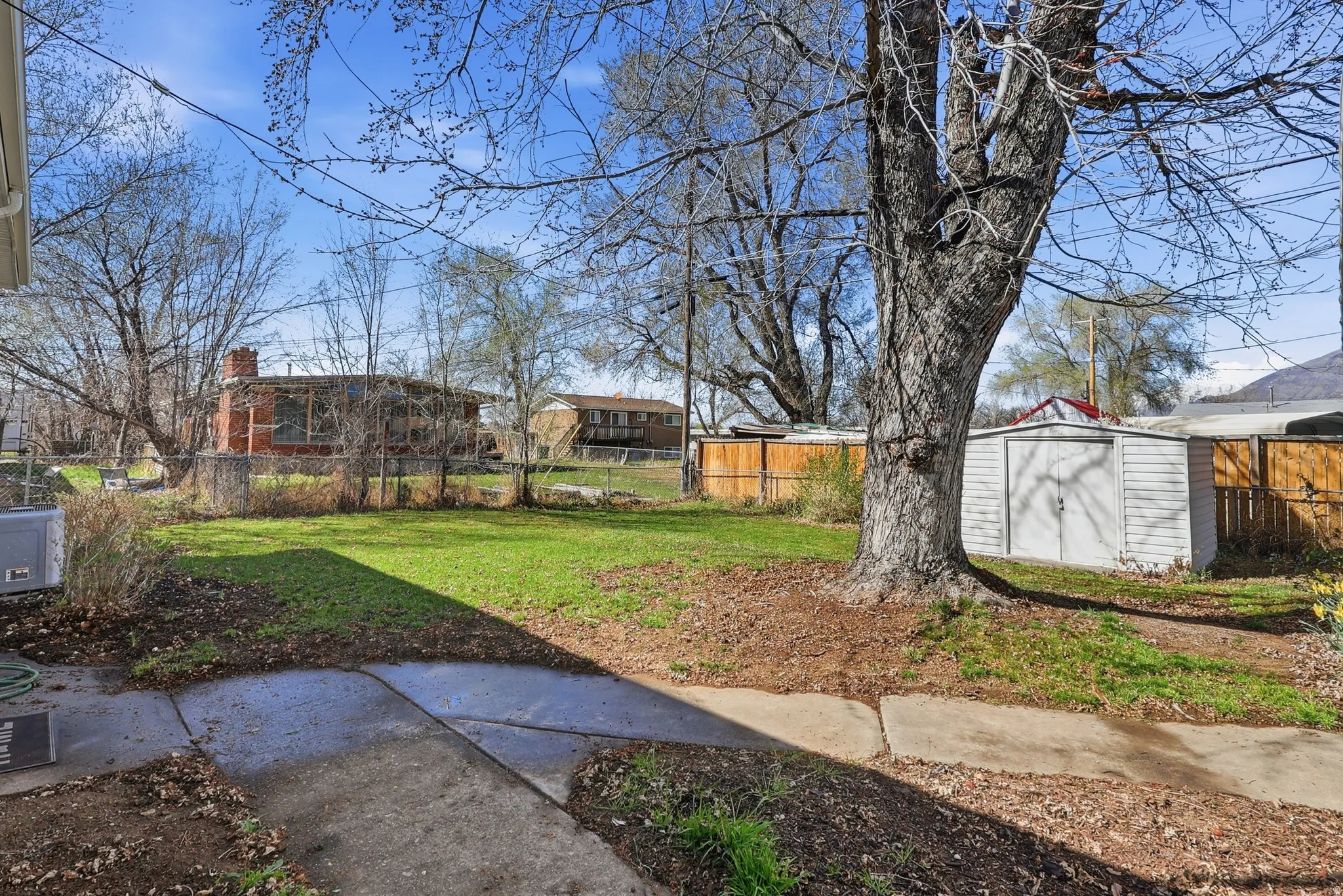 Fenced backyard featuring a storage unit