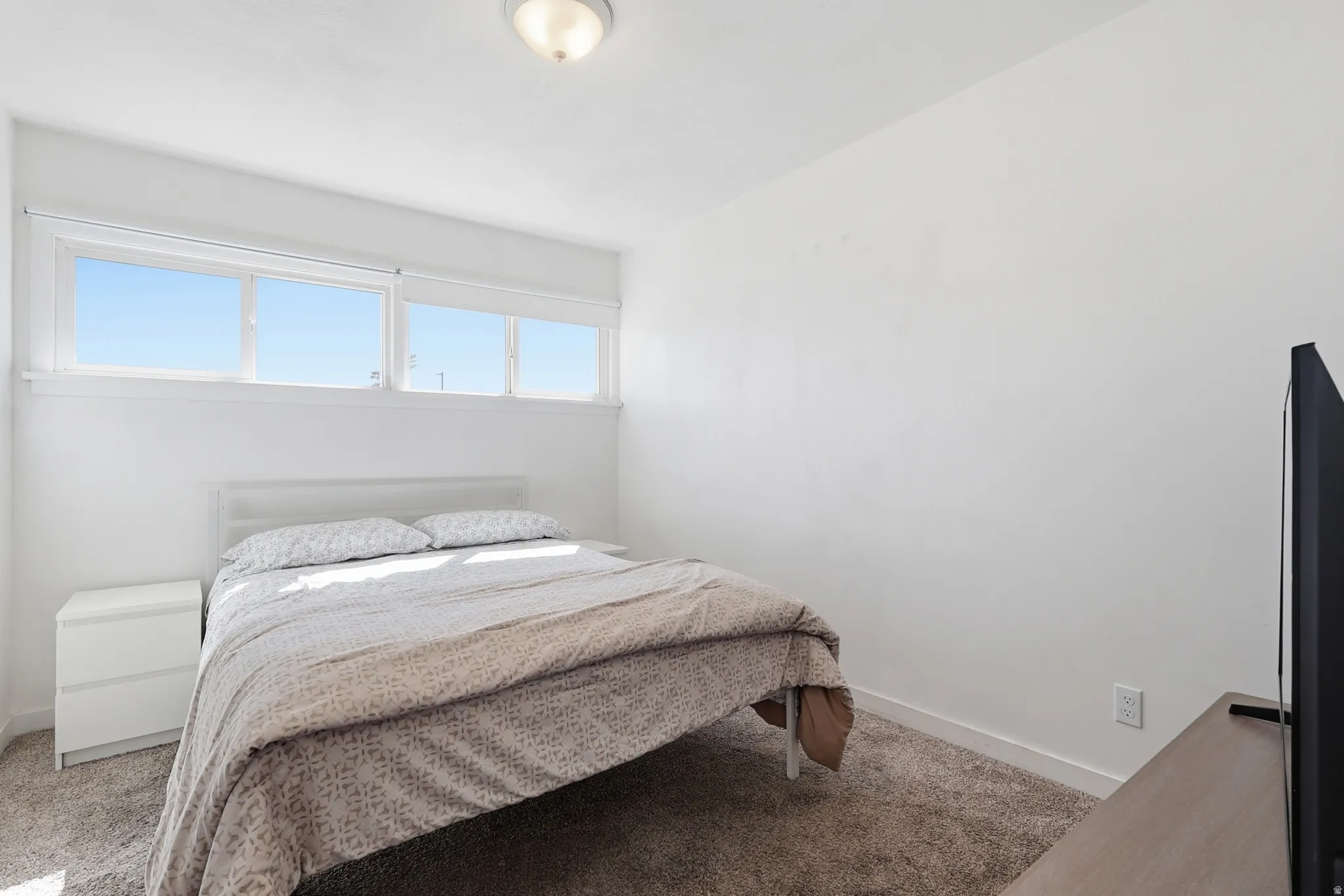 Bedroom featuring light carpet and baseboards
