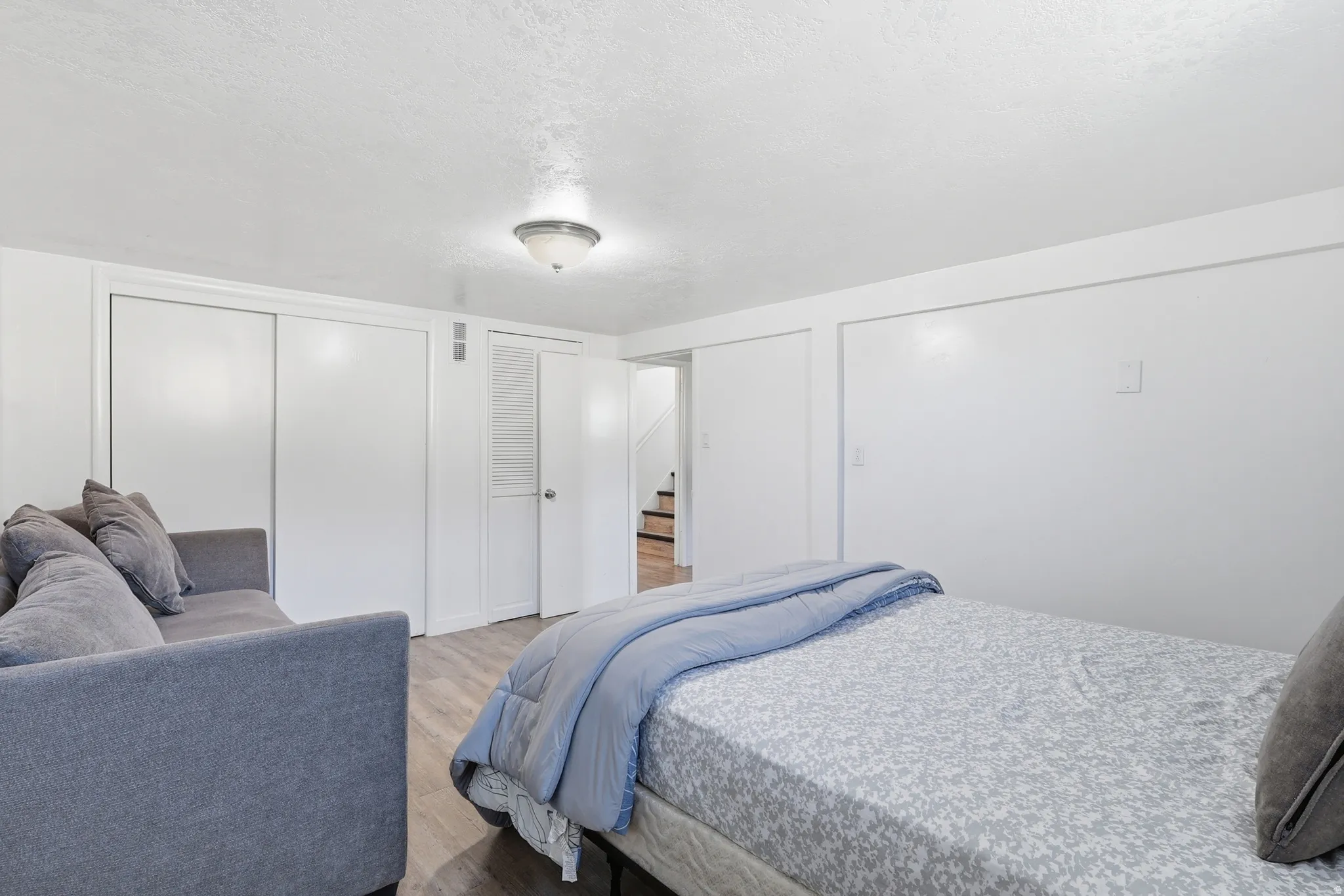 Bedroom with multiple closets, light wood-style flooring, and a textured ceiling