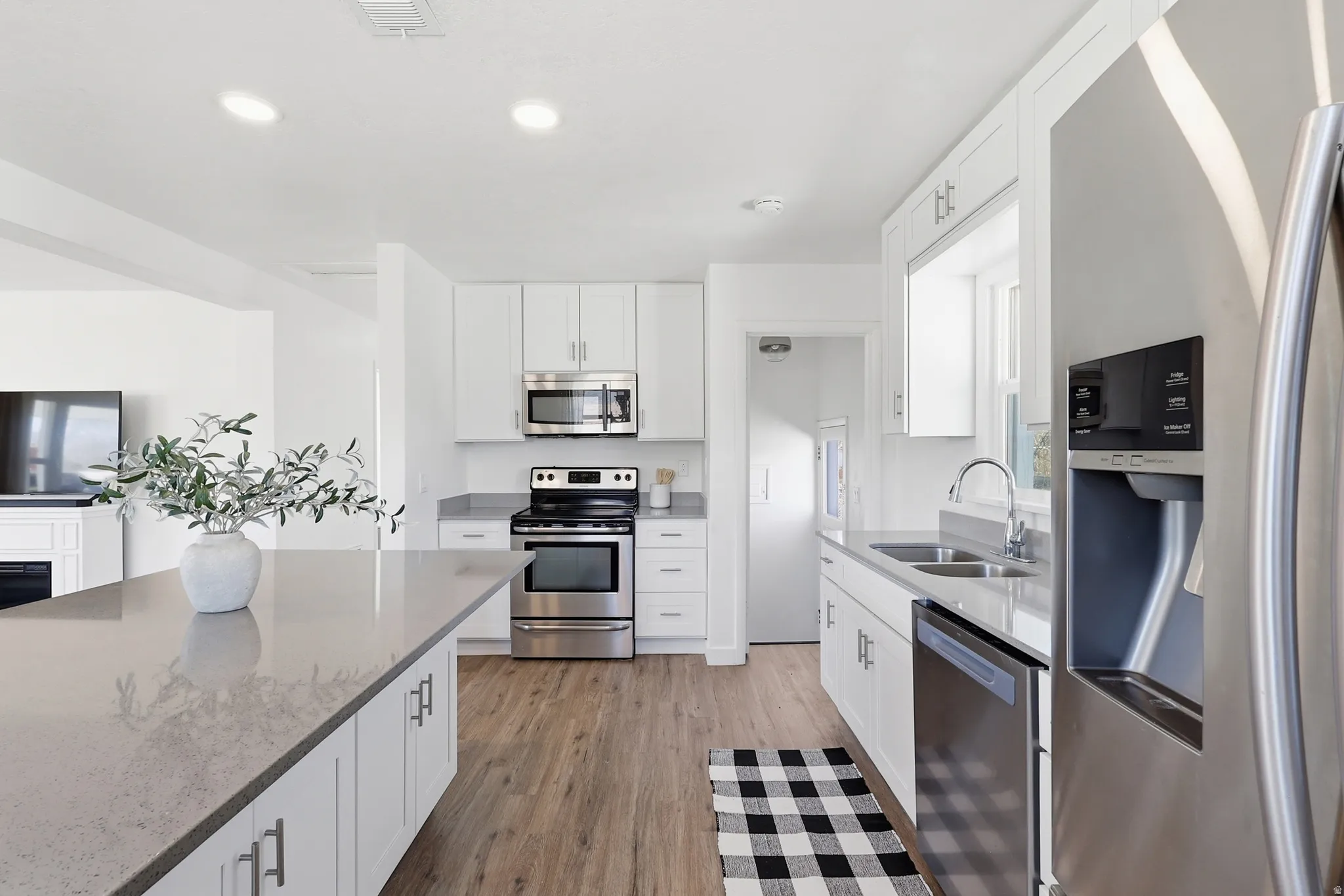 Kitchen with stainless steel appliances, white cabinets, light stone countertops, and recessed lighting