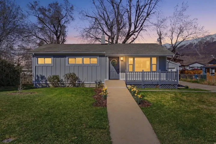 View of front of property featuring board and batten siding, a front lawn, a porch, and a chimney