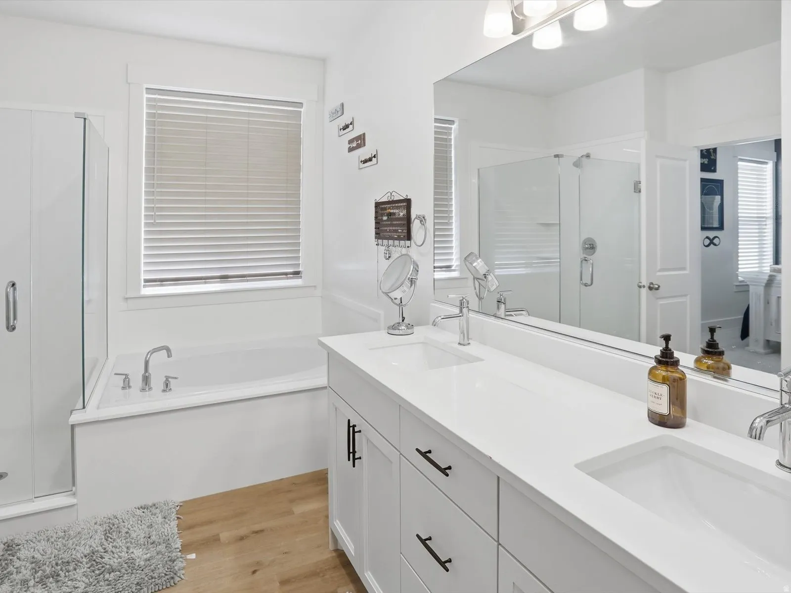 Bathroom with a stall shower, a bath, double vanity, and light wood finished floors