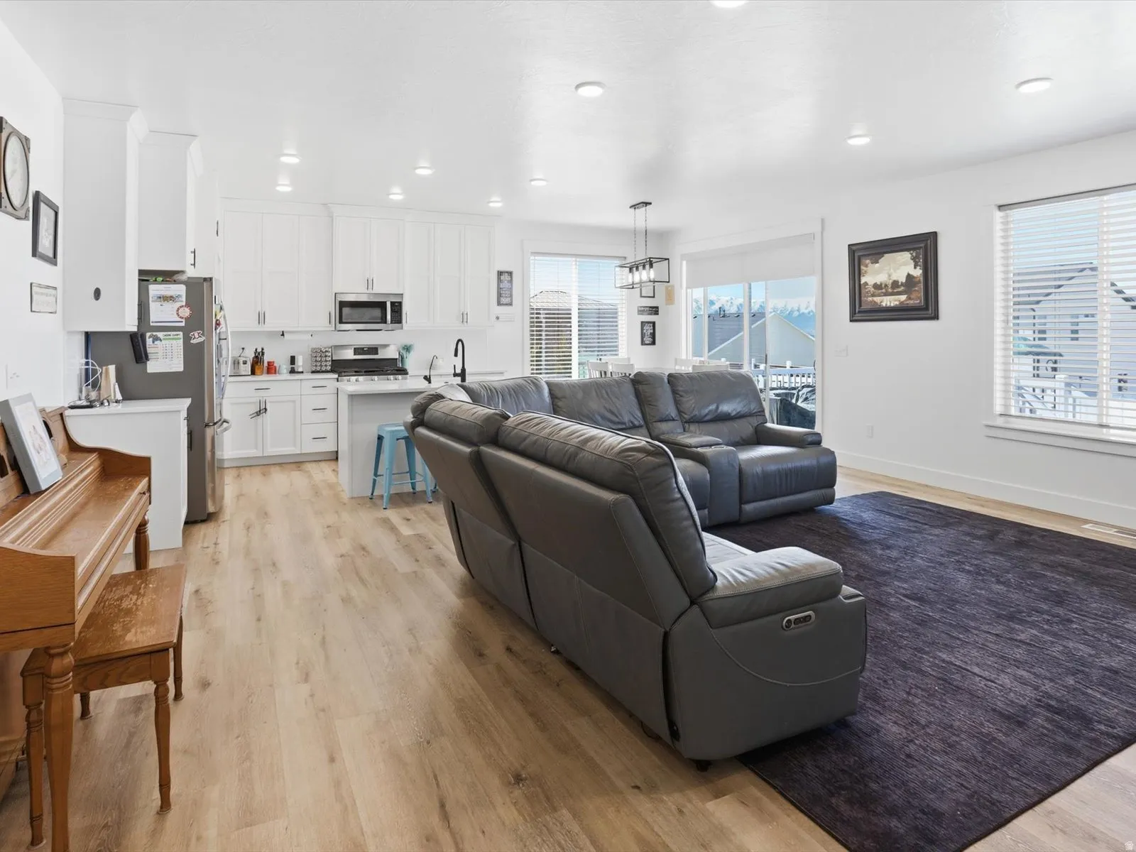 Living room with light wood finished floors and suspended lighting