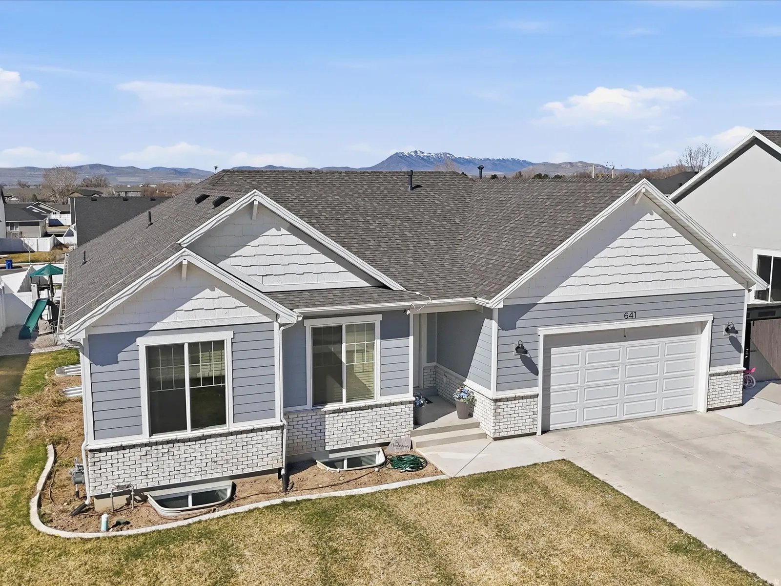 View of front of house with an attached garage, concrete driveway, a front lawn, a shingled roof, and brick siding