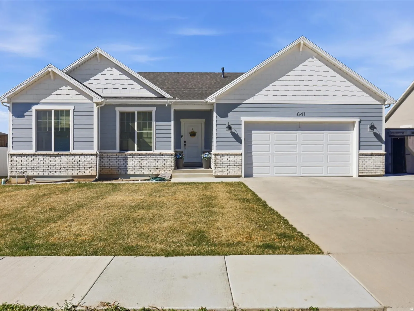 Craftsman house with a front lawn, driveway, an attached garage, and brick siding